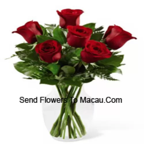 7 roses rouges avec quelques fougères dans un vase en verre