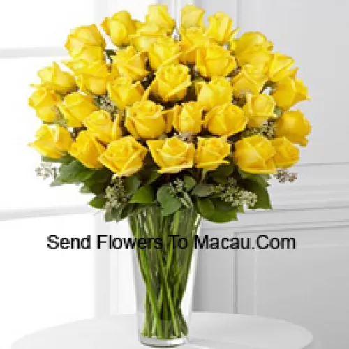 37 roses jaunes avec quelques fougères dans un vase en verre